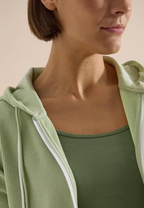 Langarm Jacke mit Kapuze und Struktur raw matcha lime Nahaufnahme einer Person, die ein grünes Tanktop und eine helle Kapuzenjacke trägt.