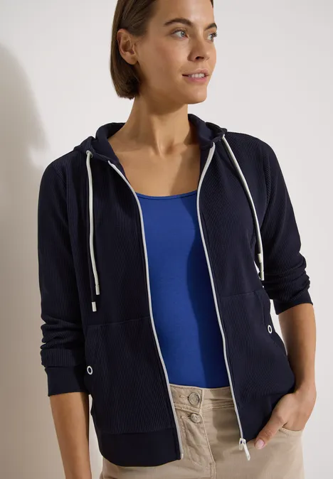Langarm Jacke mit Kapuze und Struktur urban dark blue Person trägt dunkelblaue Kapuzenjacke über blauem Top und hellen Hosen vor neutralem Hintergrund.