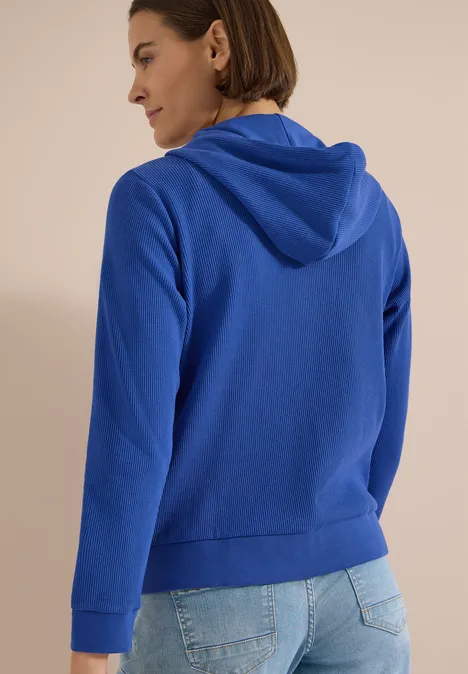 Langarm Jacke mit Kapuze und Struktur deep river blue Rückansicht einer Person in blauer Kapuzenjacke und Jeans.