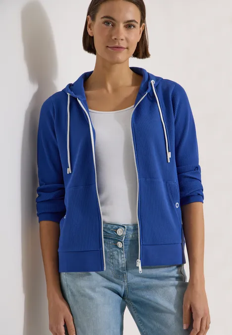 Langarm Jacke mit Kapuze und Struktur deep river blue Eine Person trägt blaue Kapuzenjacke, weißes Shirt und Jeans vor hellem Hintergrund.