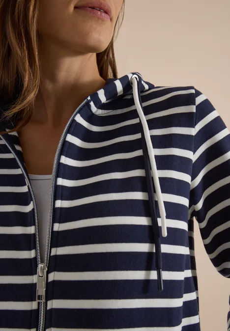 Eine Person trägt einen blau-weiß gestreiften Kapuzenpullover mit Reißverschluss.