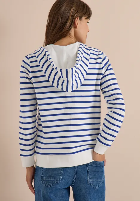 Frau von hinten in weiß-blau gestreiftem Kapuzenpullover und Jeans.