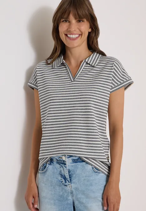 Kurzarm Poloshirt mit Streifenstruktur urban dark blue Lächelnde Frau in gestreiftem Poloshirt und hellen Jeans vor hellem Hintergrund.