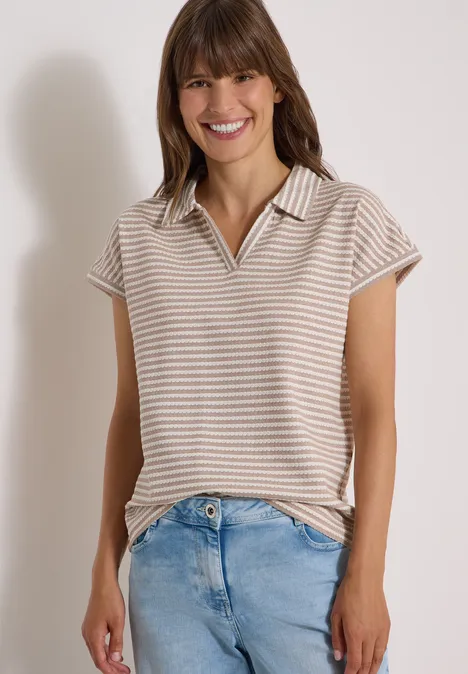 Kurzarm Poloshirt mit Streifenstruktur creamy mocha Eine lächelnde Frau in einem gestreiften Poloshirt und Jeans.