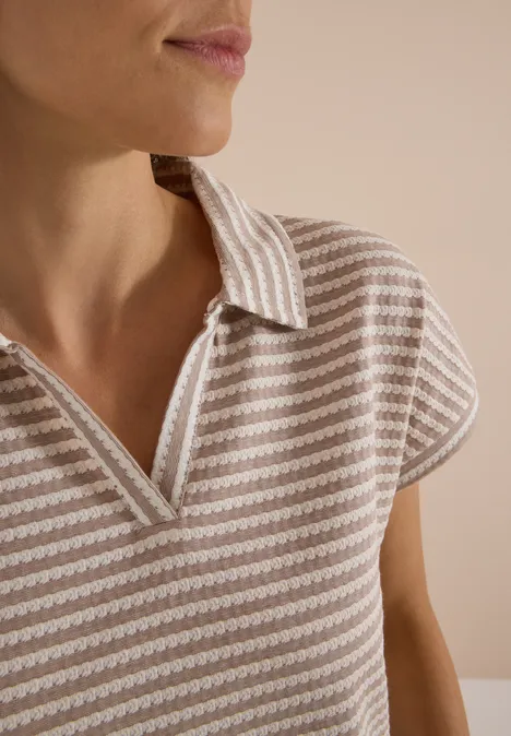 Kurzarm Poloshirt mit Streifenstruktur creamy mocha Nahaufnahme eines Oberkörpers in gestreiftem Poloshirt ohne sichtbares Gesicht.
