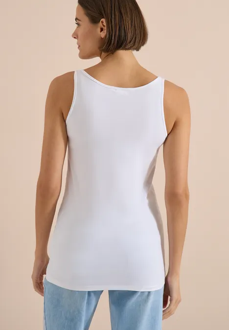 Haut long à col rond, de couleur unie White Frau von hinten in weißem Tanktop und Jeans