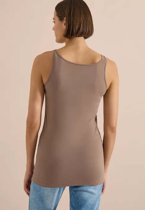 Haut long à col rond, de couleur unie cocoa taupe Rückenansicht einer Frau in ärmellosem Top und Jeans vor beigem Hintergrund.