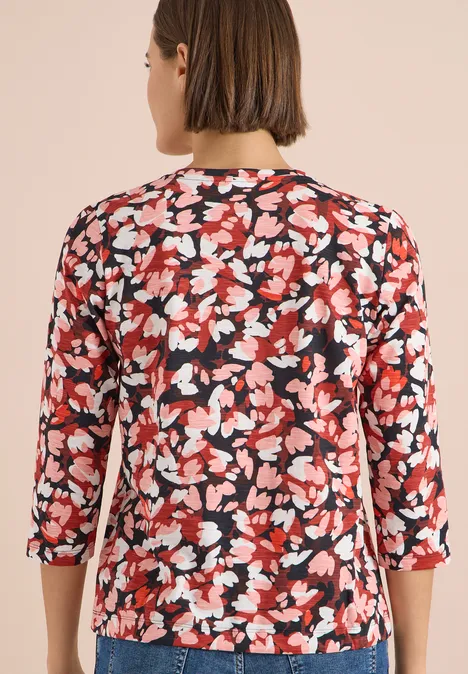 T-shirt à manches 3/4, col rond et imprimé russet red Rückansicht einer Frau in rotem Blusenshirt mit weiß-schwarzem Blumenmuster und 3/4-Ärmeln.