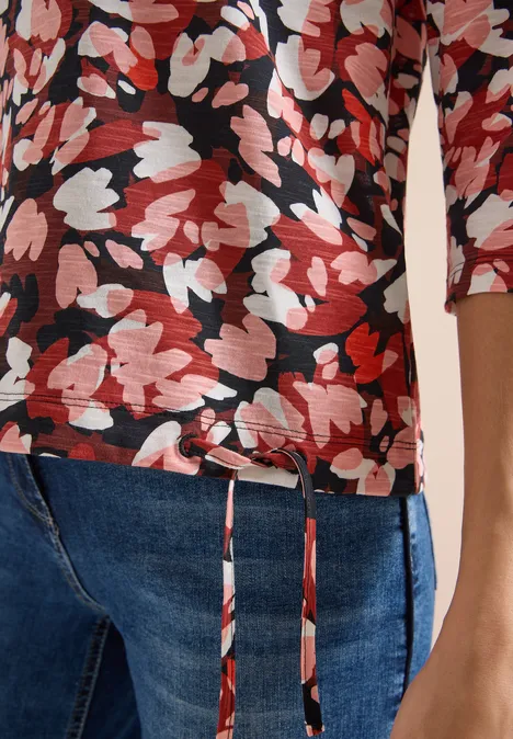 T-shirt à manches 3/4, col rond et imprimé russet red Rotes und weißes Blumenmuster auf schwarzem 3/4-Arm-Shirt kombiniert mit blauen Jeans.
