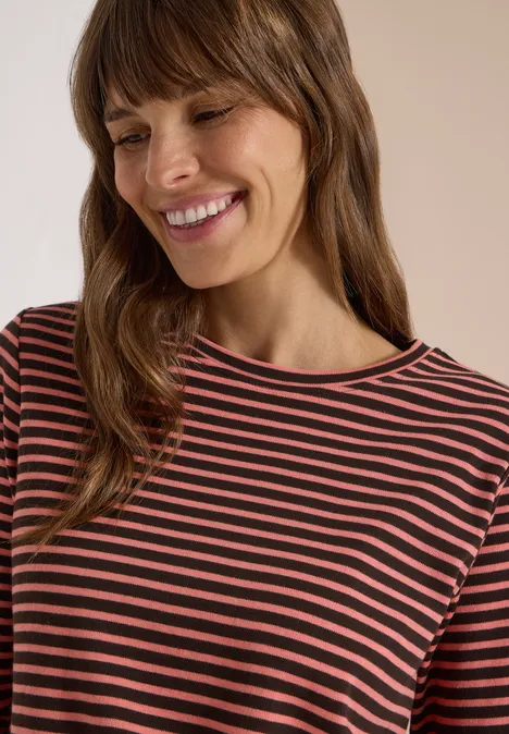 Eine lächelnde Frau mit braunen Haaren und gestreiftem Shirt.