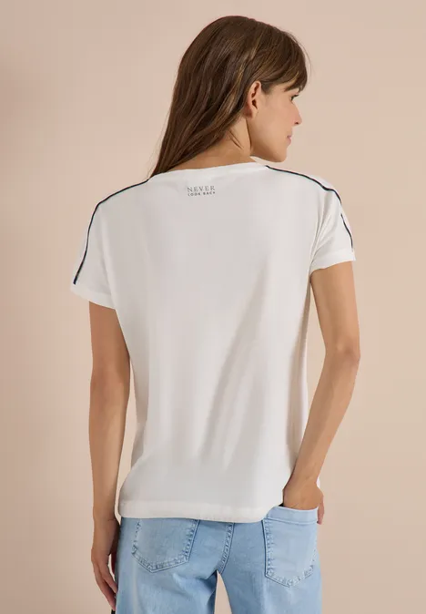 Vrouw van achteren in wit kort T-shirt met zwarte naden en een spijkerbroek voor een neutrale achtergrond.