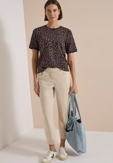 T-Shirt mit Rundhals und Leo-Muster creamy mocha Eine Frau trägt ein T-Shirt mit Leopardenmuster, eine helle Chinohose, weiße Sneaker und hält eine blaue Stofftasche.