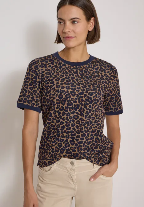 T-Shirt mit Rundhals und Leo-Muster creamy mocha Frau in kurzarm Leo-Shirt (blau-braun) und hellen Hosen vor schlichtem Hintergrund.