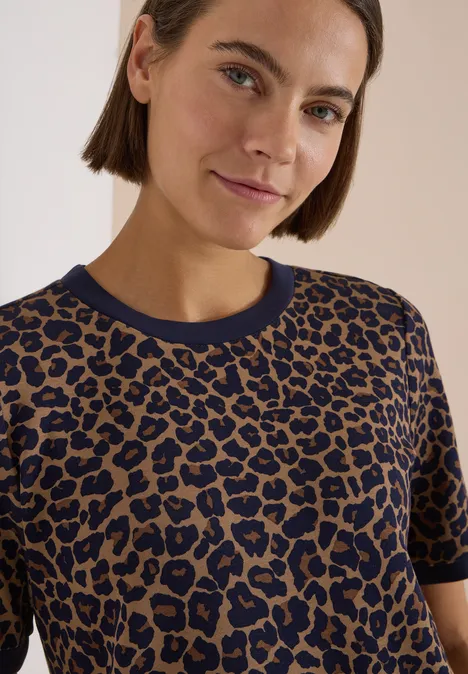 T-Shirt mit Rundhals und Leo-Muster creamy mocha Frau mit kurzen braunen Haaren trägt ein braun-blaues Leoprint-T-Shirt und blickt freundlich zur Kamera.