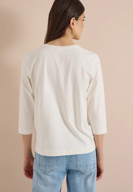 T-shirt à manches 3/4 avec inscription, style léopard vanilla white Rückansicht einer Frau in weißem Dreiviertelarm-Shirt und blauen Jeans vor hellem Hintergrund.