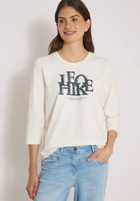 T-shirt à manches 3/4 avec inscription, style léopard vanilla white Junge Frau trägt cremeweißes Sweatshirt mit "ECO HIKE"-Print, 3/4-Ärmel und hellblaue Jeans.