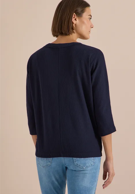 3/4-Arm Shirt mit Waffelstruktur urban dark blue Frau in marineblauem 3/4-Arm-Shirt und Jeans, Rückansicht vor neutralem Hintergrund.