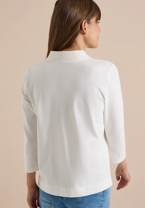 3/4-Arm Poloshirt mit Knopfdetail vanilla white Rückenansicht einer Frau in weißem Blazer mit 3/4-Ärmeln vor neutralem Hintergrund.