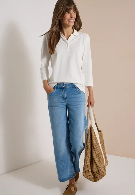 3/4-Arm Poloshirt mit Knopfdetail vanilla white Frau in weißer Bluse und weitem Jeans, lächelnd vor zweifarbiger Wand, hält Korbtasche.