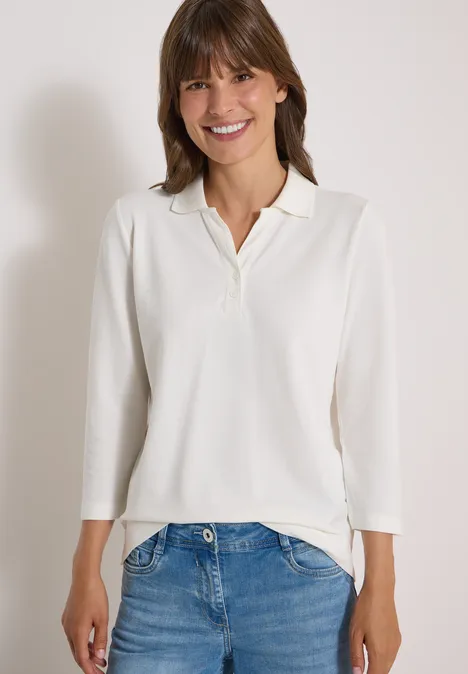 3/4-Arm Poloshirt mit Knopfdetail vanilla white Frau in weißem Langarm-Poloshirt und Jeans, lächelt vor neutralem Hintergrund.