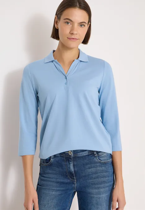 Polo à manches 3/4 avec boutons décoratifs easy blue Eine Person trägt ein hellblaues Poloshirt mit 3/4-Ärmeln und Jeans.