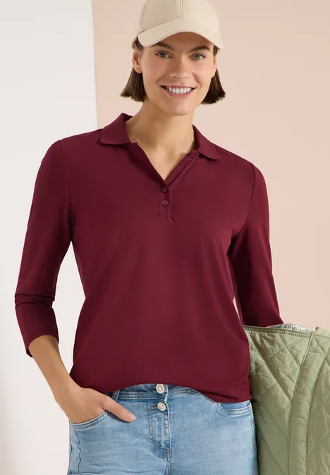3/4-Arm Poloshirt mit Knopfdetail red wine Dame trägt burgunderrote 3/4-Arm-Polobluse mit V-Knopfleiste und hellblaue Jeans, Hand in Tasche.
