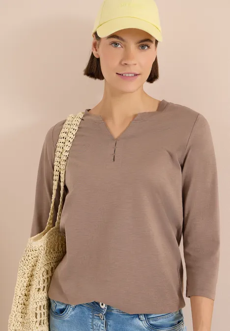 3/4-Arm Shirt mit Split Neck und Elastiksaum cocoa taupe Person trägt beigefarbenes Langarmshirt und geflochtene Tasche vor neutralem Hintergrund.
