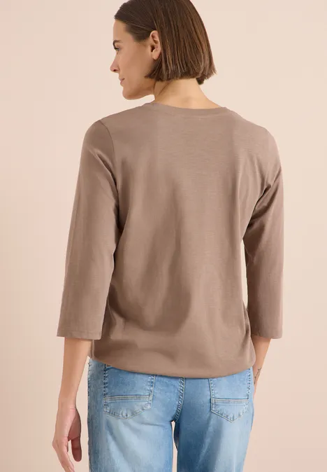 3/4-Arm Shirt mit Split Neck und Elastiksaum cocoa taupe Frau von hinten in taupefarbenem 3/4-Arm-Pullover und blauen Jeans vor neutralem Hintergrund.