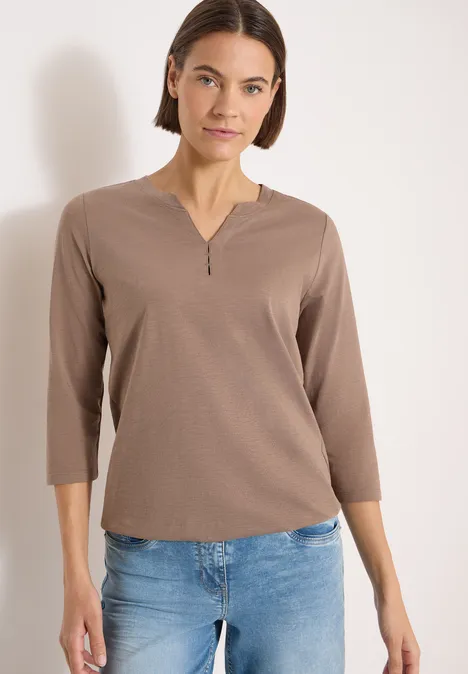 3/4-Arm Shirt mit Split Neck und Elastiksaum cocoa taupe Person trägt ein taupefarbenes 3/4-Shirt mit kurzem Reißverschluss am Kragen und blaue Jeans vor hellem Hintergrund.