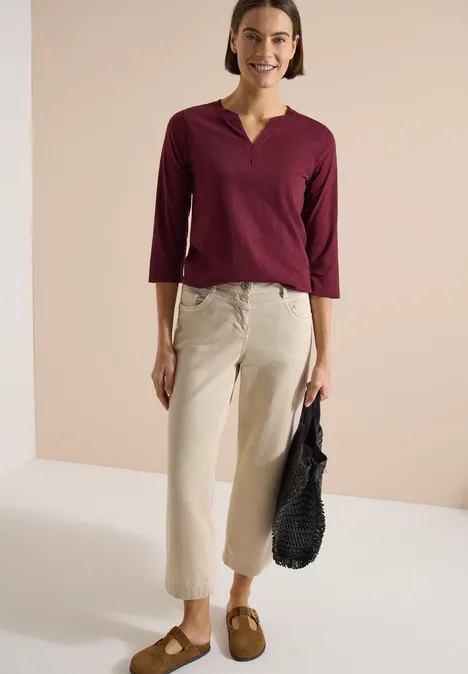 3/4-Arm Shirt mit Split Neck und Elastiksaum red wine Frau in bordeauxrotem 3/4-Ärmel-V-Shirt, beigefarbenen Culottes, braunen Slippern und schwarzer Tasche.