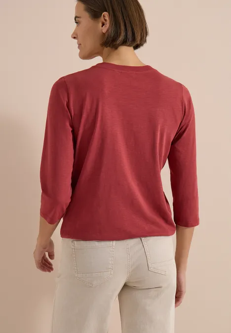 3/4-Arm Shirt mit Split Neck und Elastiksaum russet red Eine Person in rotem Dreiviertelarm-Shirt und heller Jeans, von hinten vor neutralem Hintergrund.