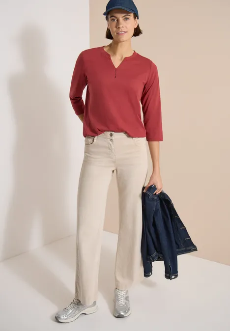 3/4-Arm Shirt mit Split Neck und Elastiksaum russet red Person in rotem 3/4-Arm-Shirt, beigen Schlaghosen und silbernen Sneakern, hält eine Jeansjacke in der Hand.