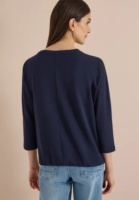 Batwing Shirt mit Leo-Pipings urban dark blue Frau von hinten in marineblauem 3/4-Arm-Oberteil vor neutralem Hintergrund.