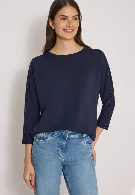 Batwing Shirt mit Leo-Pipings urban dark blue Eine lächelnde Frau in dunkelblauem Dreiviertelarm-Shirt und Jeans vor weißem Hintergrund.