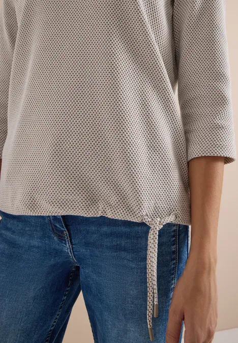 3/4-Arm Shirt mit Rundhals und Struktur natural taupe Person trägt beige, grobmaschigen Pullover mit seitlicher Schleife und blaue Jeans.
