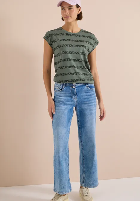 T-Shirt mit Rundhals und Leo-Streifen dried olive green Person trägt weite blaue Jeans und ein gestreiftes grün-schwarzes T-Shirt vor hellem Hintergrund.