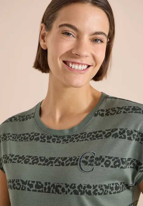 T-Shirt mit Rundhals und Leo-Streifen dried olive green Person mit kurzem Haar trägt grünes T-Shirt mit schwarzen Leopardenstreifen und Kreislogo vor hellem Hintergrund.