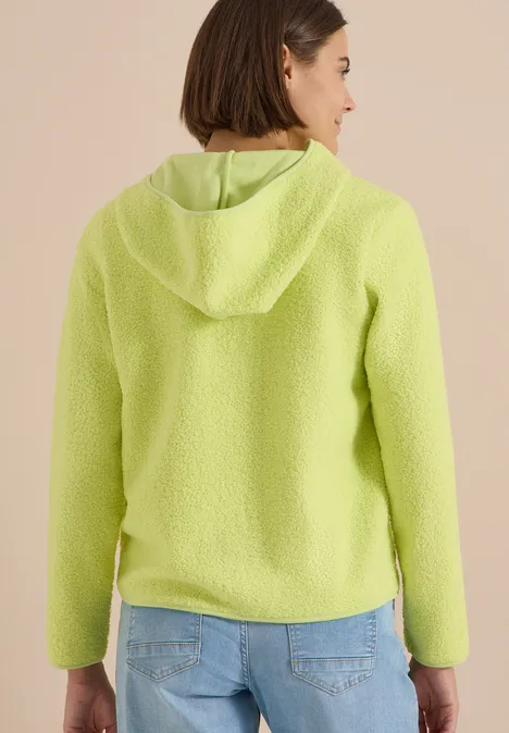 Frau in hellgrüner Fleecejacke mit Kapuze, gesehen von hinten.