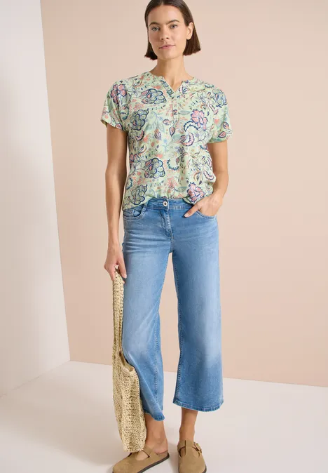 Shirt met split in de hals en print raw matcha lime Vrouw in kleurrijk paisley-blouse, lichte cropped wijde jeans en gouden tas.