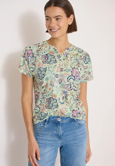 Shirt met split in de hals en print raw matcha lime Persoon met kleurrijk, gemusterd kort shirt en blauwe spijkerbroek voor lichte achtergrond
