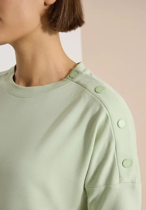 Dropped Shoulder Shirt mit Knöpfen raw matcha lime Nahe Aufnahme eines hellgrünen Oberteils mit einem Rundhalsausschnitt und dekorativen Knöpfen auf der Schulter.