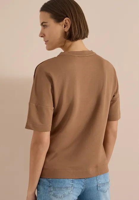 Dropped Shoulder Shirt mit Knöpfen creamy mocha Rückenansicht einer Frau mit kurzärmligem, braunem Oberteil und blauer Jeans