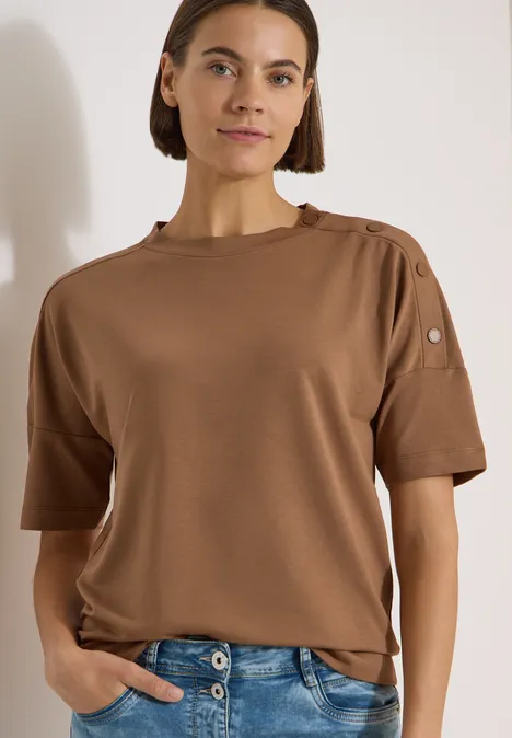 Dropped Shoulder Shirt mit Knöpfen creamy mocha Person trägt braunes T-Shirt mit kurzen Ärmeln und Knöpfen an der Schulter.