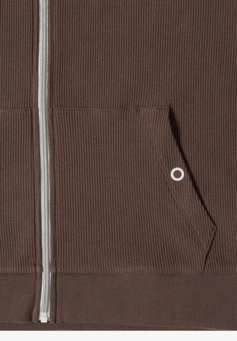 Nahaufnahme eines braunen Reißverschluss-Sweatshirts mit Kängurutasche und Rippenstruktur.