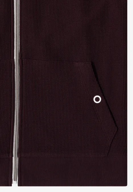 Veste à manches longues, à capuche et texturée berry red Nahaufnahme eines dunkelroten Kapuzenpullovers mit Reißverschluss und Fronttasche
