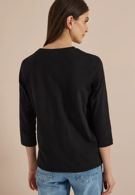 3/4-Arm Shirt mit Rundhals in Unifarbe Black Rückansicht einer Frau mit schwarzem Dreiviertelarm-Shirt und Jeans vor hellem Hintergrund.