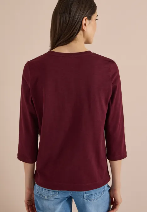 3/4-Arm Shirt mit Rundhals in Unifarbe red wine Rückansicht einer Person in einem bordeauxroten Dreiviertelarmshirt und blauen Jeans vor neutralem Hintergrund.