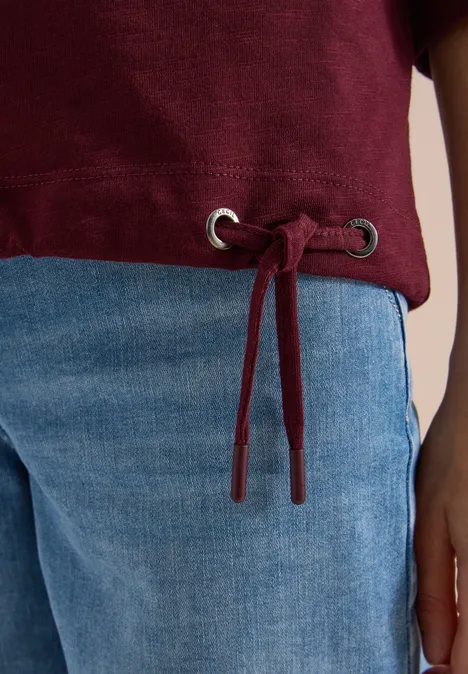 3/4-Arm Shirt mit Rundhals in Unifarbe red wine Eine hellblaue Jeans und ein bordeauxroter Pulli mit Kordelzug und silbernen Ösen am Saum.