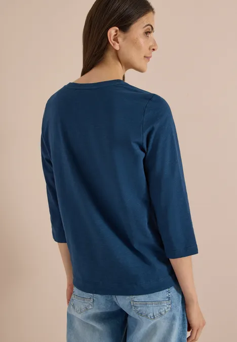 3/4-Arm Shirt mit Rundhals in Unifarbe moonlight blue Eine Frau in Jeans und dunkelblauer 3/4-Arm-Bluse mit Rundhalsausschnitt, seitlich von hinten fotografiert.