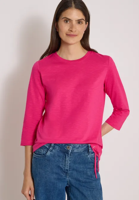 3/4-Arm Shirt mit Rundhals in Unifarbe pink flash Frau in pinkem Langarmshirt und Jeans, frontal stehend vor hellem Hintergrund